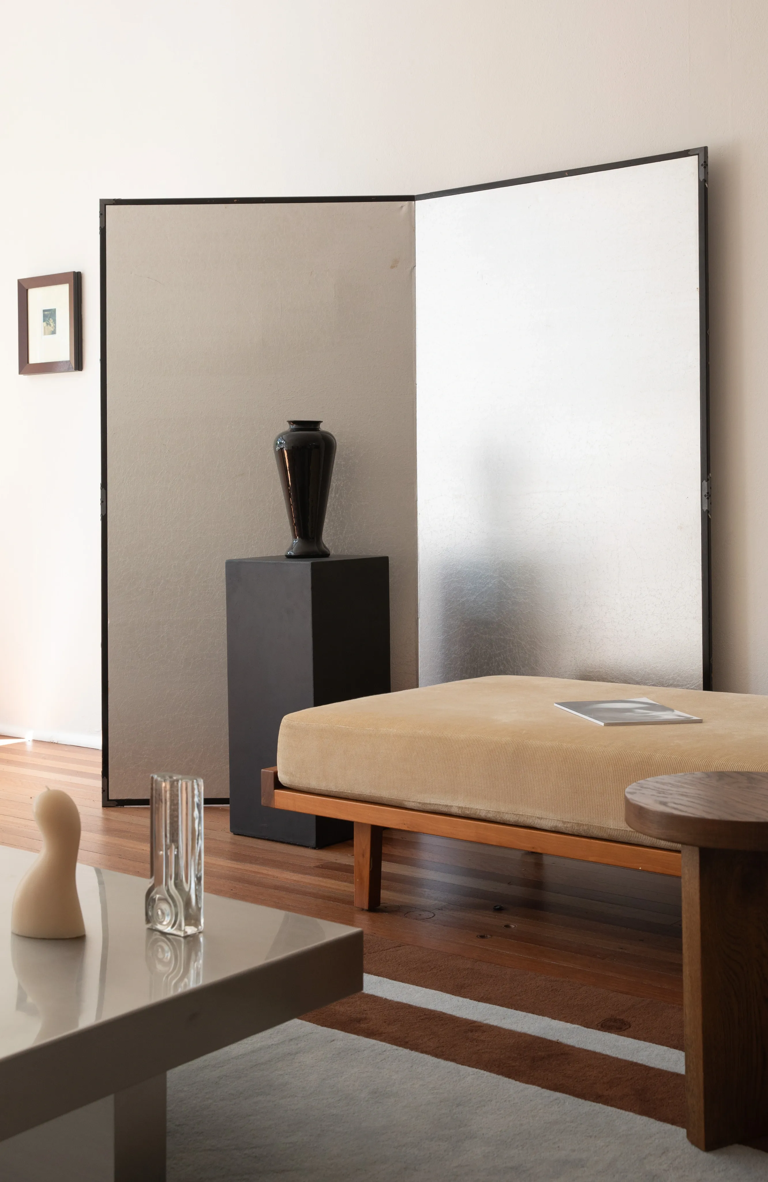 A sculptural timber armchair beside a folding screen